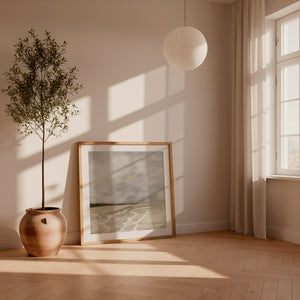 Whispers of Light limited edition paper print in oak frame leaning against wall with olive tree – abstract seascape wall art DT Art Studio.