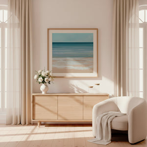 Coastal Azure limited edition paper print in oak frame above timber sideboard in sunlit cream living room – abstract seascape wall art DT Art Studio.