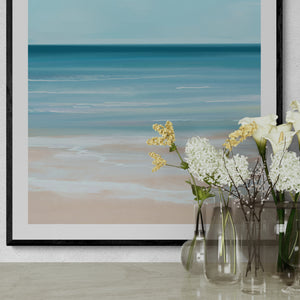 Close-up of Coastal Azure abstract seascape paper print in black frame with white flowers – limited edition coastal wall art DT Art Studio.